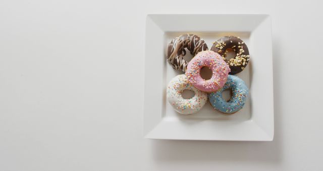 Image of donuts with icing on white plate over white background. colourful fun food, candy, snacks and sweets concept.