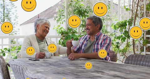 Senior Couple Enjoying Coffee Surrounded by Smiling Emojis