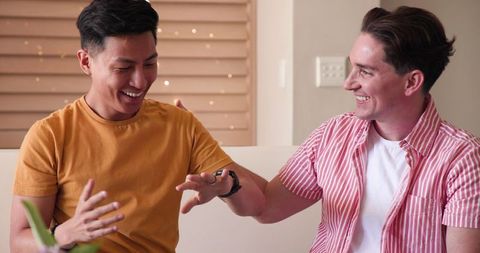 Joyful couple celebrating engagement with rings and laughter at home