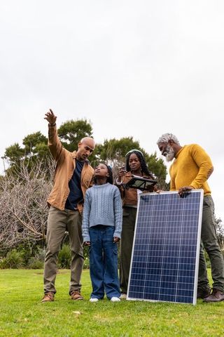 Multigenerational african american family exploring solar energy with panel and tablet