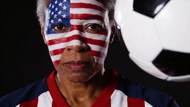 Senior woman with usa flag face paint and soccer ball showing fierce fan determination