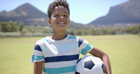 Smiling Boy with Soccer Ball in Sunlit Park