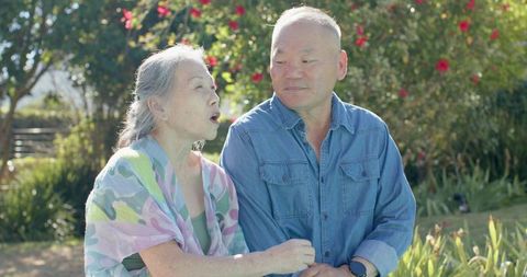 Senior chinese couple sitting together in sunny garden sharing conversation and warmth