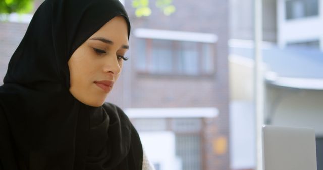 Focused Muslim Woman Working on Laptop in Modern Office Setting - Download Free Stock Images Pikwizard.com