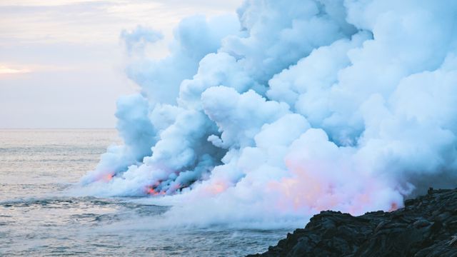 Close-up of volcanic lava flowing into the ocean and generating thick clouds of steam. Suitable for visualizing natural phenomena, geological studies, and the raw power of nature. Ideal for science presentations, environmental education, and travel blogs focusing on volcanic regions.