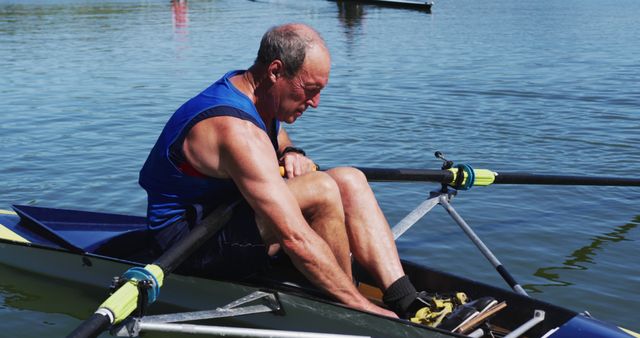 Senior caucasian man preparing rowing boat in a river. sport retirement leisure hobbies rowing healthy outdoor lifestyle.