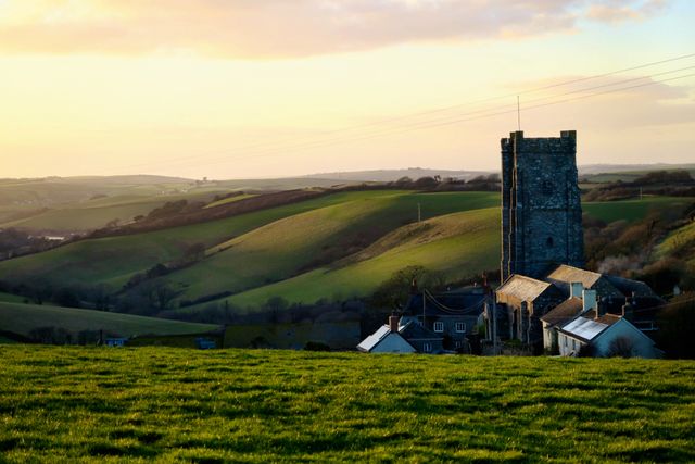 Village church standing tall amid rolling green hills in evening light captures tranquility and scenic beauty, ideal for themes of rural architecture, calm, and pastoral life. This setting is perfect for articles, guides, travel blogs, and nature magazines depicting serene countryside environments.