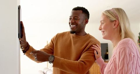 Smiling Couple Using Smart Home Touchscreen in Bright Living Room