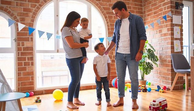 Young family enjoying playtime in bright loft playroom with toys and bunting