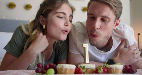 Couple sharing grapes celebrating relationship anniversary with cupcakes