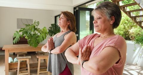 Mature Women Practicing Yoga at Home with Plants and Natural Light