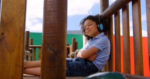 Relaxed Biracial Boy Enjoying Music on Playground in Headphones