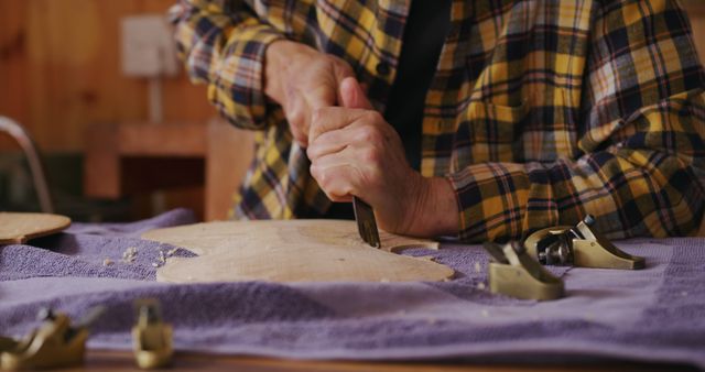 A skilled craftsman is carving a piece of wood in a workshop. Sanginstrument usage and tool arrangement emphasizes careful craftsmanship and dedication to traditional woodworking techniques. This scene suggests themes of craftsmanship, tradition, and skilled labor, making it suitable for promoting DIY craft hobbies, artisan tool brands, and vocational training materials.