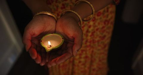 Woman holding lit diya celebrating traditional indian festival