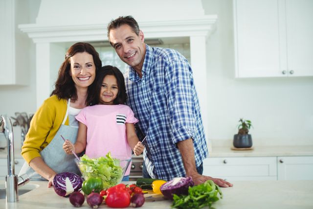 Portrait of parents and daughter preparing salad in kitchen at home