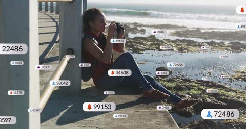 Woman photographing scenic coastal view at oceanfront