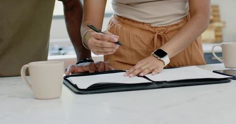Indian woman and african american man reviewing documents on marble kitchen countertop