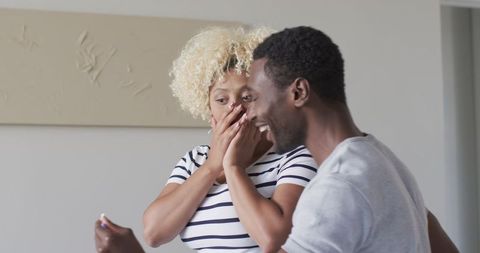 Excited afro-descendant couple sharing surprise moment at home