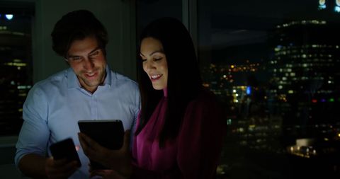 Smiling Office Executives Discussing Over Tablet at Night