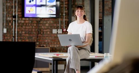 Smiling Businesswoman Using Laptop in Modern Collaborative Office Space
