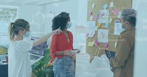 Team collaborating with futuristic digital interface in office during pandemic