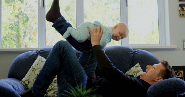 Father Playing and Lifting Baby in Cozy Living Room - Download Free Stock Images Pikwizard.com