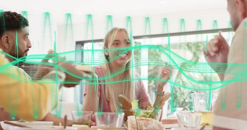 Smiling blonde woman sharing meal with friends around sunlit modern dining table
