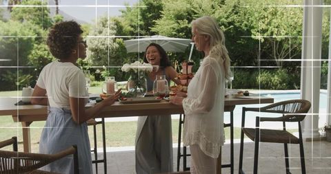 Three Women Enjoying Sunlit Garden Brunch by Pool Laughing Over Pastries