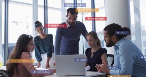 Business team collaborating around laptop with social media notification overlays