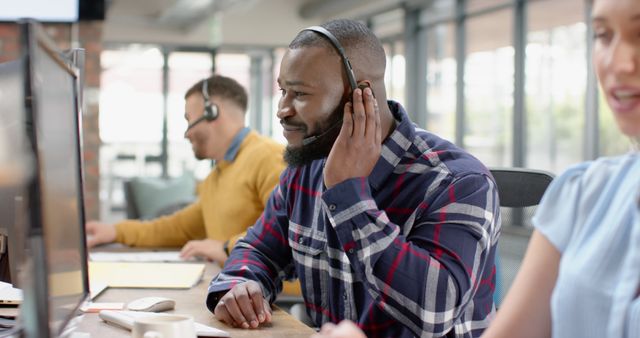 Showing diverse customer service team working in an open, modern office environment. Useful for depicting collaborative team environments, customer support roles, and corporate office scenarios.