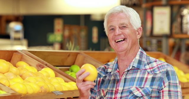 Senior man smiling while choosing large yellow apples in the grocery store fruit section. Great for articles on senior lifestyle, healthy eating, and grocery shopping tips. Ideal for promoting supermarkets, healthy diet campaigns, and senior care services.