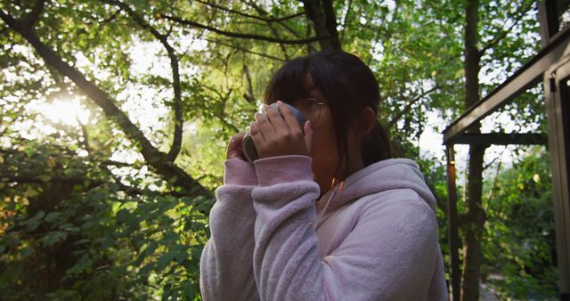 Asian girl drinking tea in garden and smiling. at home in isolation during quarantine lockdown.