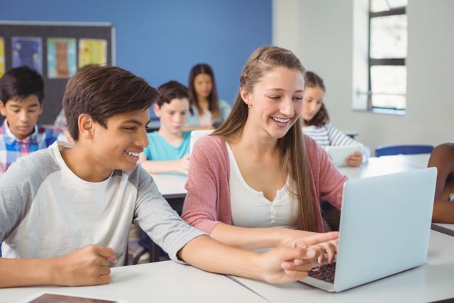 Students are collaborating on a laptop in a classroom, showcasing modern digital learning and teamwork. This image can be used for educational websites, school brochures, technology in education articles, and promotional materials for academic institutions.