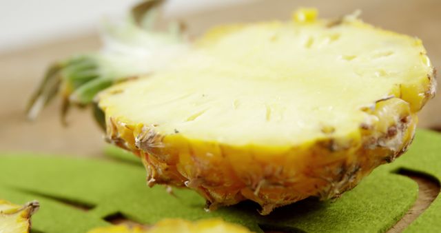 A fresh pineapple slice rests on a green cutting board, with copy space. Its vibrant yellow flesh and textured rind suggest a juicy and tropical flavor ready to be enjoyed.