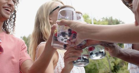 Friends toasting with fresh berry drinks at summer gathering