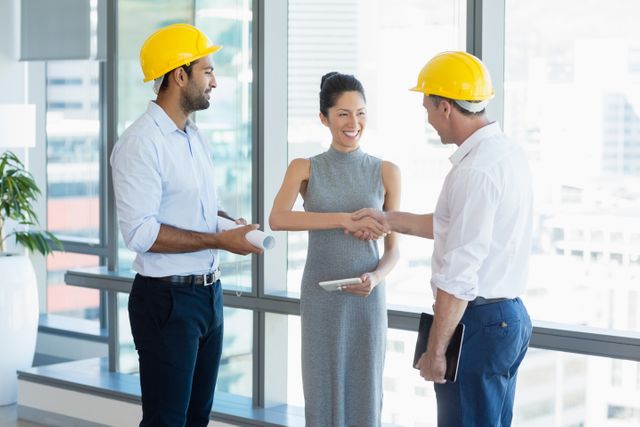 Architects in a modern office shaking hands, symbolizing successful collaboration and teamwork. Ideal for use in business, construction, and professional partnership contexts, as well as for illustrating concepts of agreement, project planning, and corporate success.