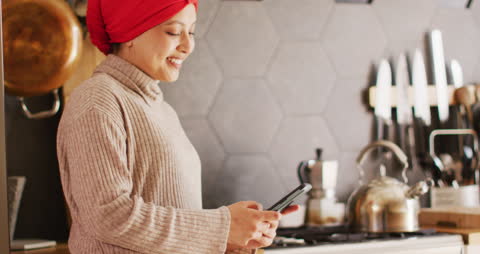 Smiling Woman in Hijab Using Smartphone in Kitchen