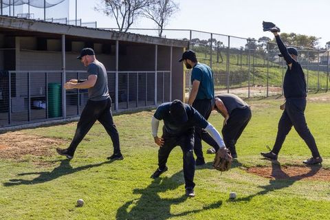 Baseball players practicing infield fielding drills on sunny grass during team training