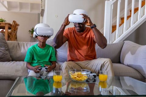 African American Father and Son Playing Virtual Reality Games on Living Room Couch