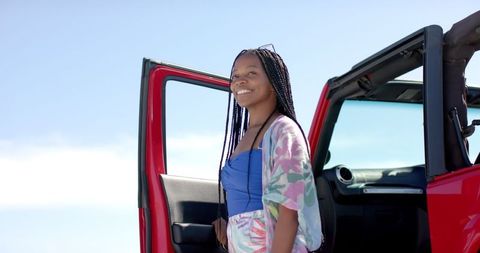 Smiling woman enjoying road trip by red convertible
