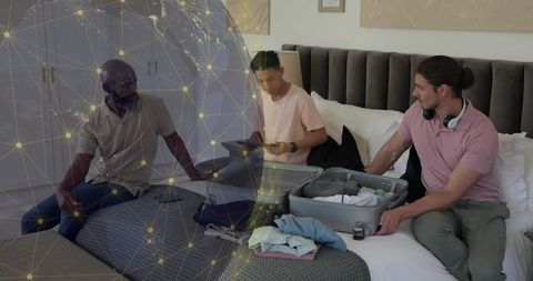 Three men unpacking suitcase on bed while using devices with global network overlay