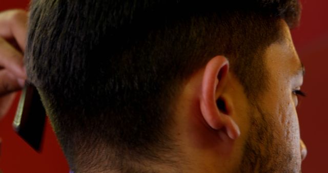 Focus is on the close-up view of the back of a male's head while receiving a haircut with clippers. Ideal for use in articles or advertisements related to haircuts, barber services, grooming tips, haircare products, and barbershop promotions.