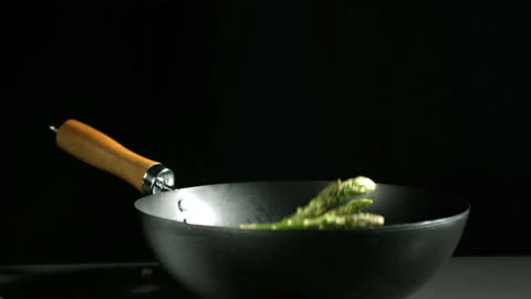 Fresh Asparagus Falling into Hot Wok in Slow Motion