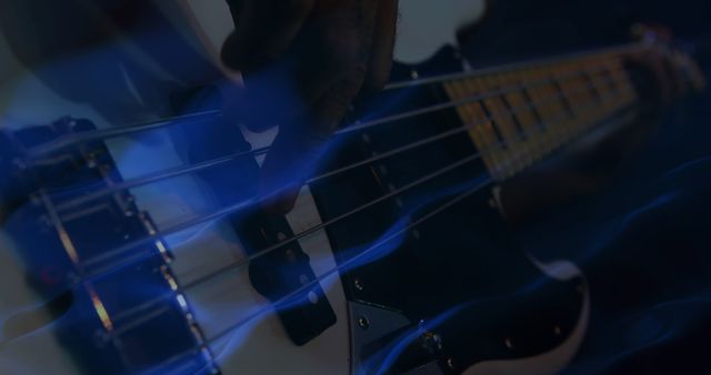 Detailed view showing hand strumming strings of electric bass guitar, accompanied by dramatic blue light. Ideal for use in music-related content, articles, blogs, album covers, social media posts, and promotional materials for live performances.