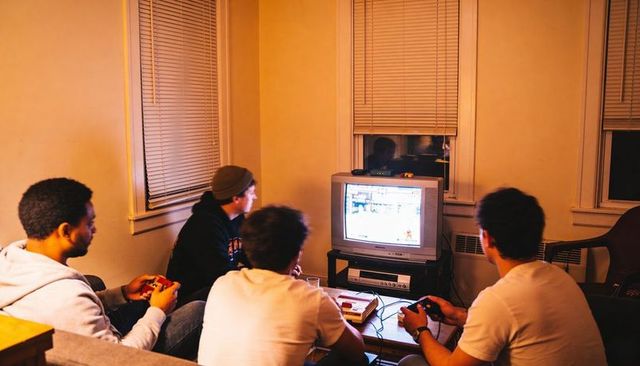Friends playing retro console games on crt television in cozy apartment lounge at night
