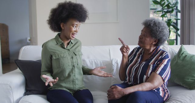 Sad african american adult daughter and senior mother having disagreement at home, slow motion. Family, motherhood and domestic life, unaltered.