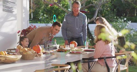 Multigenerational Family Gathering on Sunlit Patio Around Long White Dining Table