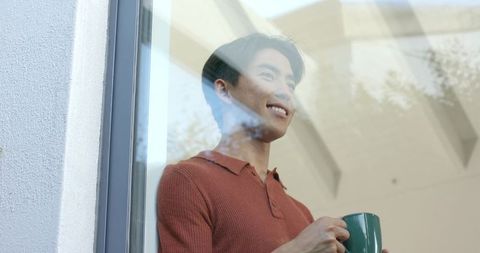 Man Looking Out Window with Mug in Airy Modern Space