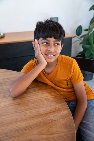 Young Boy Relaxing at Home Beside Potted Plant in Sunny Interior