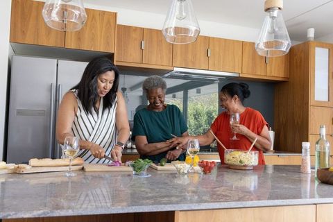 Multigenerational african american women preparing dinner together in modern kitchen